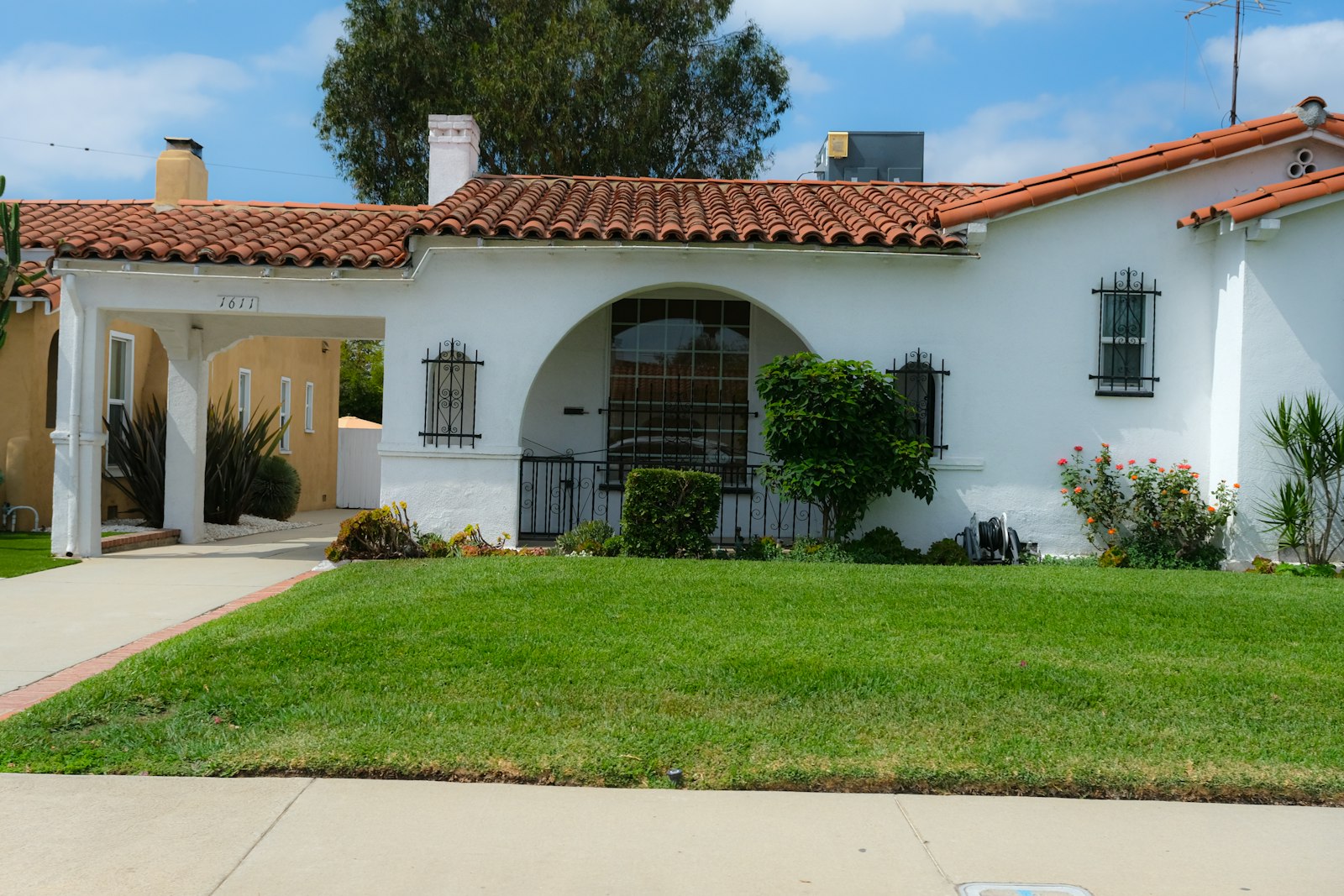 Stucco house with a tile roof and a green front lawn